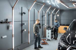 Empleados en interior de un taller de automoviles bien iluminado usando luminarias LED